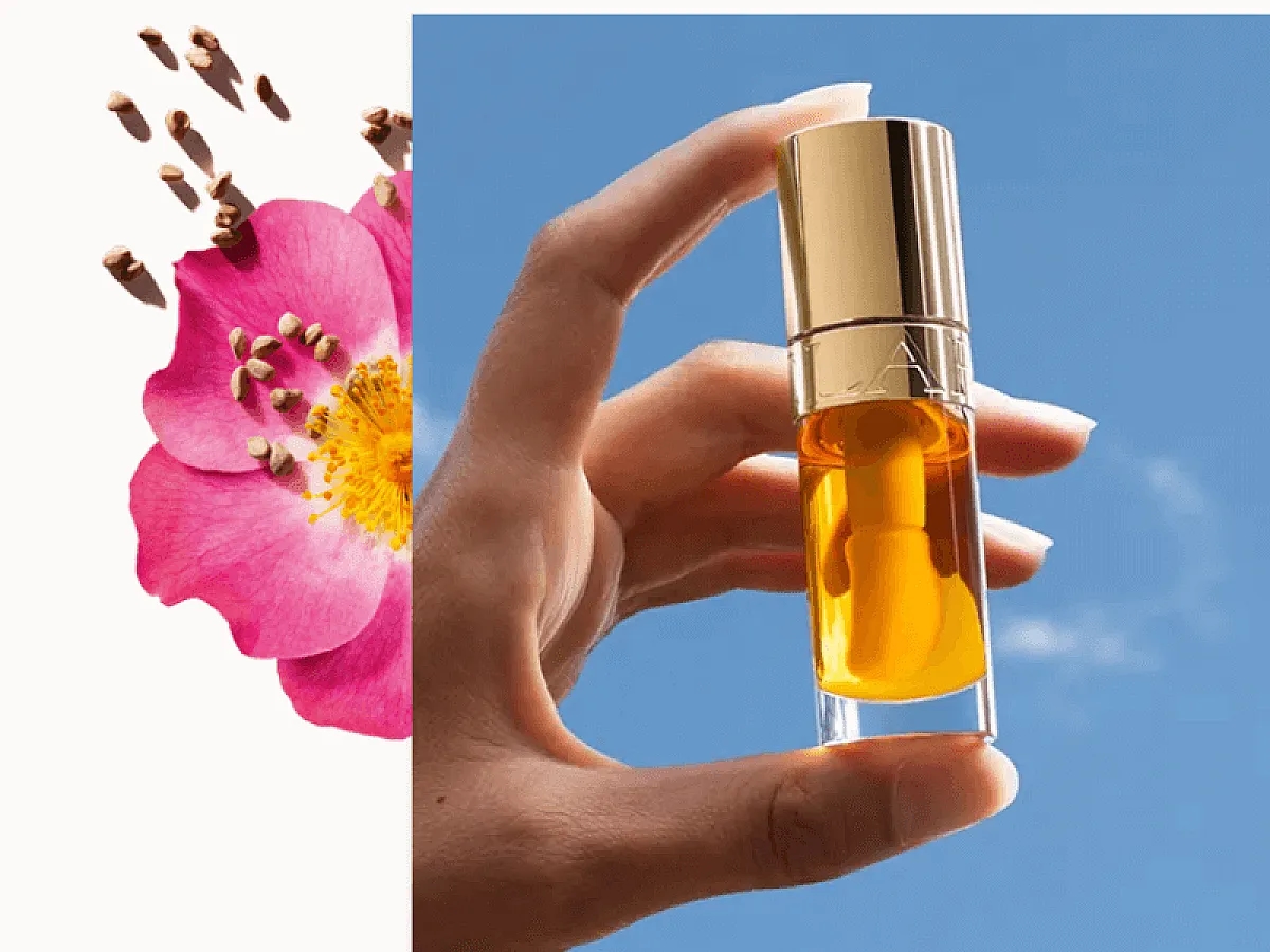 La main tient le classique de Clarins : L'huile pour les lèvres au miel