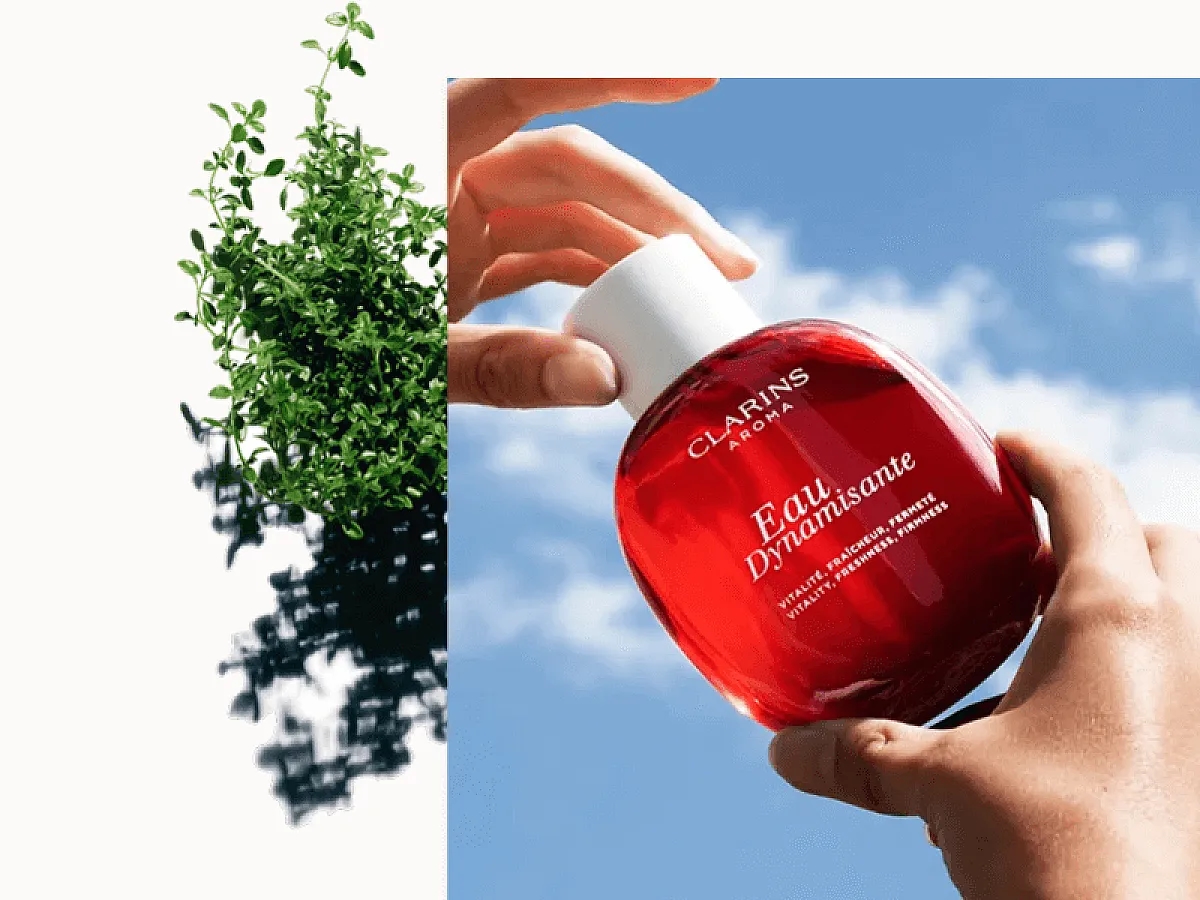 70 ans de Clarins : Des mains qui tiennent l'Eau Dynamisante de Clarins devant un ciel d'un bleu éclatant