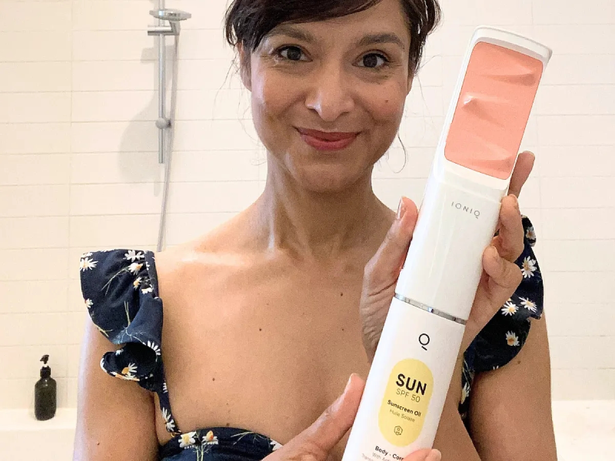 Woman holding the ONE Sprayer from IONIQ Skincare with the SUN cartridge with SPF 50