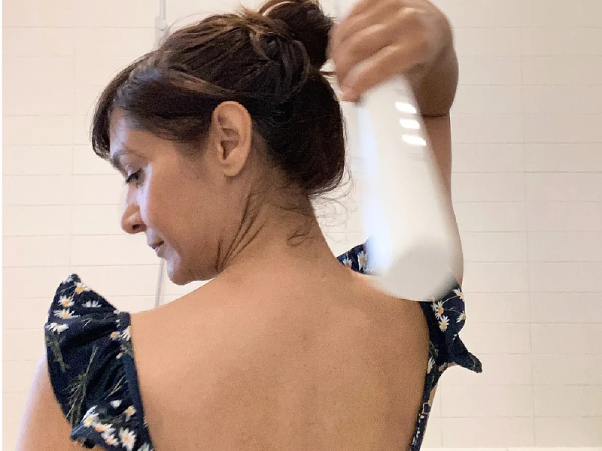 IONIQ skincare experience report: Woman holds the ONE Sprayer over her head to apply cream to her back