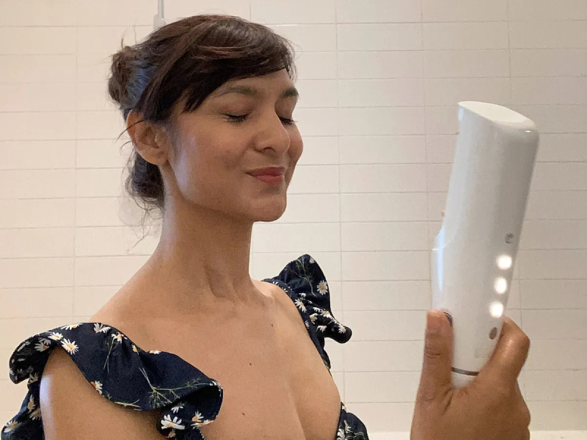 Woman sprays sunscreen on her face with the help of ONE from IONIQ Skincare